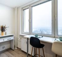 Dining area by the window with a view, two chairs, in a two-room apartment with wood-patterned flooring.