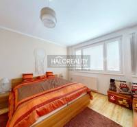 A bedroom with wood-patterned flooring in a 2-room apartment, cozy orange accessories.