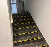 Staircase with support railing, marked with warning tapes in commercial premises.