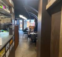 Interior of a dining area with plates on a shelf, blackboards, tables, and chairs.