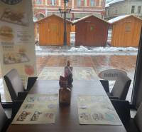 Winter scenery through the window of a gastro space with a view of wooden tables.