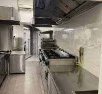 Professional kitchen with stainless steel appliances and white tiles in the gastro area.