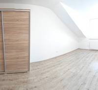 A bright room with white walls and a wardrobe, floor with wooden decor.