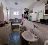 A bathroom in a family house with a shower, sink, and cabinets.