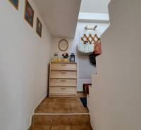 Hallway of a family house with stairs, wooden furniture, decorations, and wall hooks.