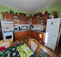 A kitchen in a family house with wooden furniture and decorations on the shelves.