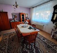 Dining room with solid wood furniture, clock on the wall, floor with wooden decor, family house.
