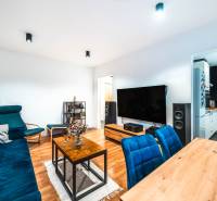 A living room of a two-room apartment with a wooden decor floor and blue sofas.