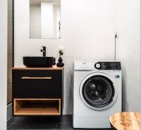 A bathroom in a 2-room apartment with a sink, washing machine, and black accessories.