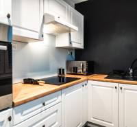 A kitchen in a 2-room apartment with white cabinets and a black wall.