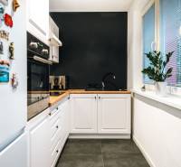 A kitchen in a 2-room apartment with a black wall, wooden decor, and white cabinets.