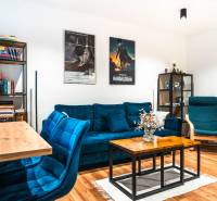 Living room of a two-room apartment with a blue sofa, a bookshelf, and a wooden decor floor.