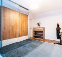 A room in a 2-room apartment with a wooden decor floor, a wardrobe, and a desk.