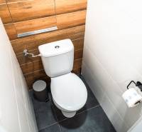 A toilet in a 2-room apartment with wooden decor and white tiles.