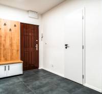 Hallway in a 2-room apartment with tiles, a wooden coat rack, and white doors.
