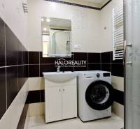 Bathroom with a washing machine and a shower in a 2-room apartment, light tiles, patterned floor tiles.