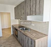 A kitchen in a 2-room apartment with a wooden decor floor and tiles on the wall.