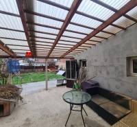 The terrace of a family house in Komárno with garden furniture and a shelter.