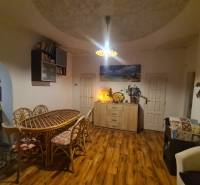 Interior of a family house with a wooden decor floor, a large table, and decorations.