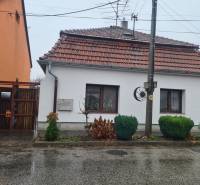 A family house in Komárno with a white facade and a tiled roof, surrounded by greenery.