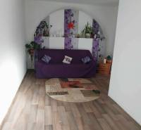 Living room in a family house with a purple sofa and a wood-patterned floor.