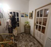 A hallway of a family house with a chair, wall pictures, and a coat rack.