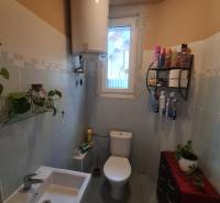 A bathroom in a family house with sanitary facilities, a water heater, and a window.