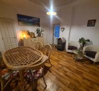 Interior of a family house with a wooden decor floor, a wicker table, and comfortable armchairs.