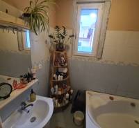 Bathroom in a family house with a bathtub, mirror, and shelf for toiletries.