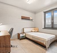 A bedroom in a family house with simple furnishings, a desk, and a comfortable bed.