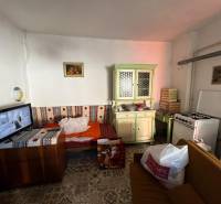 A room with a sofa, kitchen unit, stove, and television in a family house.