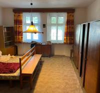 A bedroom in a family house with carpeted flooring and furniture in light colors.