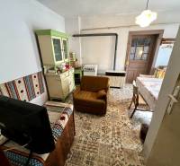 A living room in a family house with rustic furniture and patterned flooring.