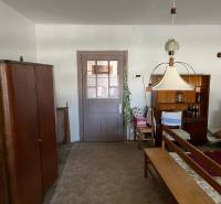 Interior of a family house with furniture and a carpet, a central lamp, and a shelf with drinks.
