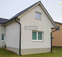 A family house in Kľačno with a white facade and a sloped roof on a well-maintained lawn.
