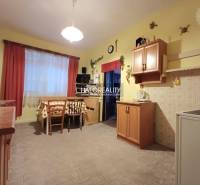 A kitchen in a family house with a wooden decor, dining table, and cabinets.