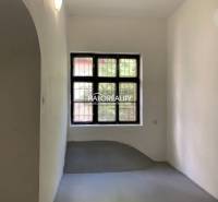 A narrow room with white walls, a window with bars, a gray floor in the office.