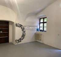 An office interior with white walls, a window, wall decoration, and a wooden shelf.