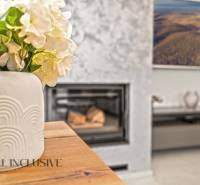 A vase with flowers on the table, a floor with a wooden design, a fireplace in a family house.