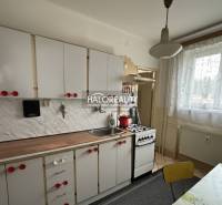 A kitchen in a 3-room apartment with white cabinets and a kitchen counter with a wood decor.