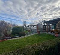 Gardens of Spišská Nová Ves with trimmed bushes, lawn, and wooden shelter.
