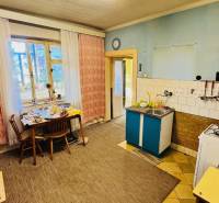 A kitchen in a family house with a dining table, a gas stove, and a sink.