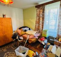 A room in a family house with clutter, old furniture, and a view through the window.
