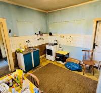 A kitchen in a family house with blue walls, older furniture, and practical equipment.