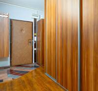 A hallway with wooden decor wardrobes in a 4-room apartment, doors with a security lock.