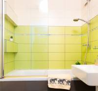 A bathroom in a 4-room apartment with a bathtub, sink, and green tiles.