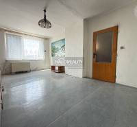 Spacious living room in a 3-room apartment, white wall, wooden doors and furniture.