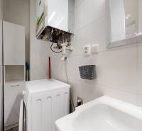Bathroom of a 3-room apartment with appliances, a sink, and a mirror on the wall.