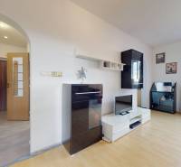 Living room in a three-room apartment with a wooden decor floor, light furniture set.
