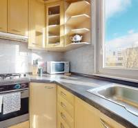 A kitchen in a 3-room apartment with wooden cabinets, a gas stove, and a view from the window.